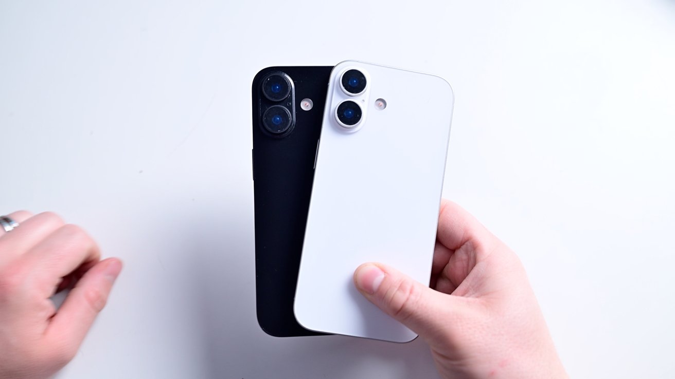 Two hands hold black and white smartphones, each with three cameras on the back, against a plain white background.